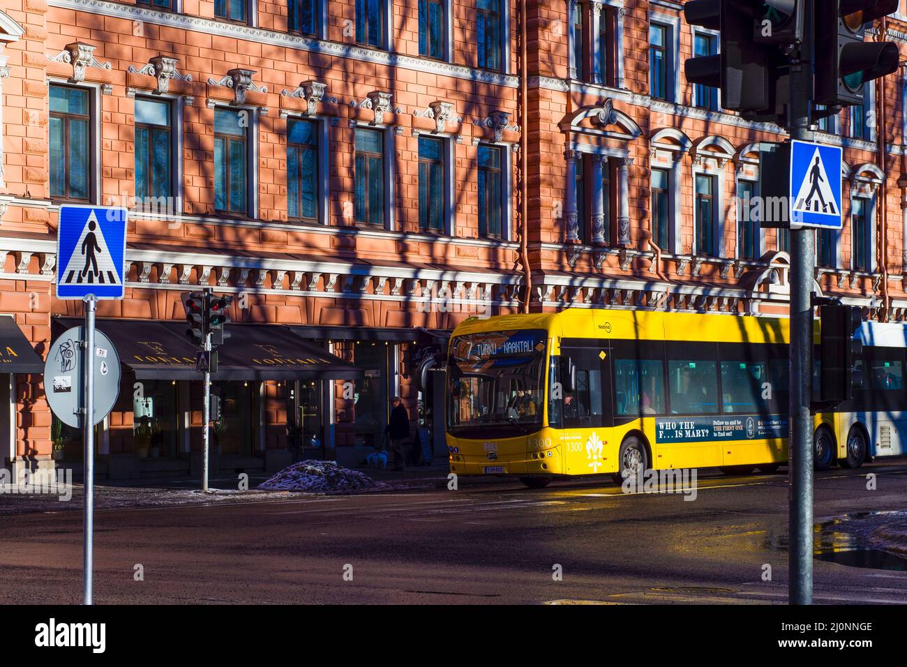 Gelber öffentlicher Bus im Stadtzentrum von Turku, betrieben von Föli. Kreuzung von Straßen mit einem vorbeifahrenden Autobus. Stockfoto