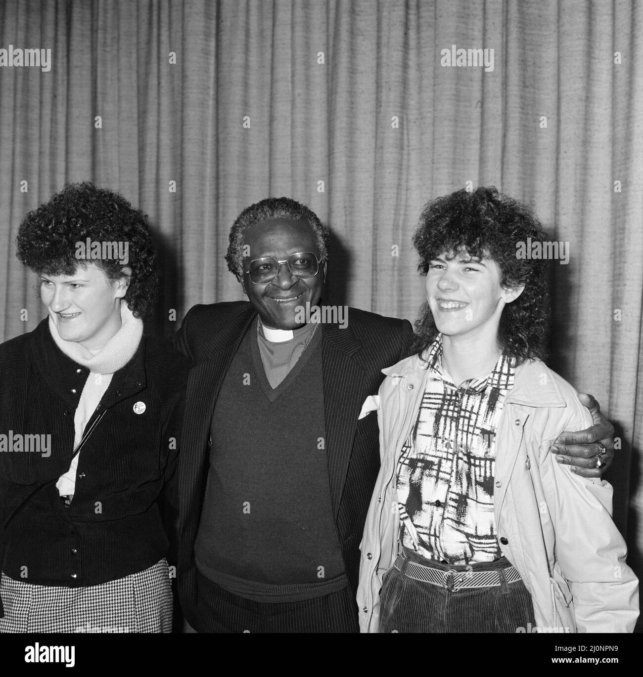 Bischof Desmond Tutu am Flughafen London, auf dem Weg nach Oslo, um seinen Nobelpreis zu erhalten, flankiert von irischen Frauen, Mary Manning (links) und Karen Gearon. 8.. Dezember 1984. Stockfoto