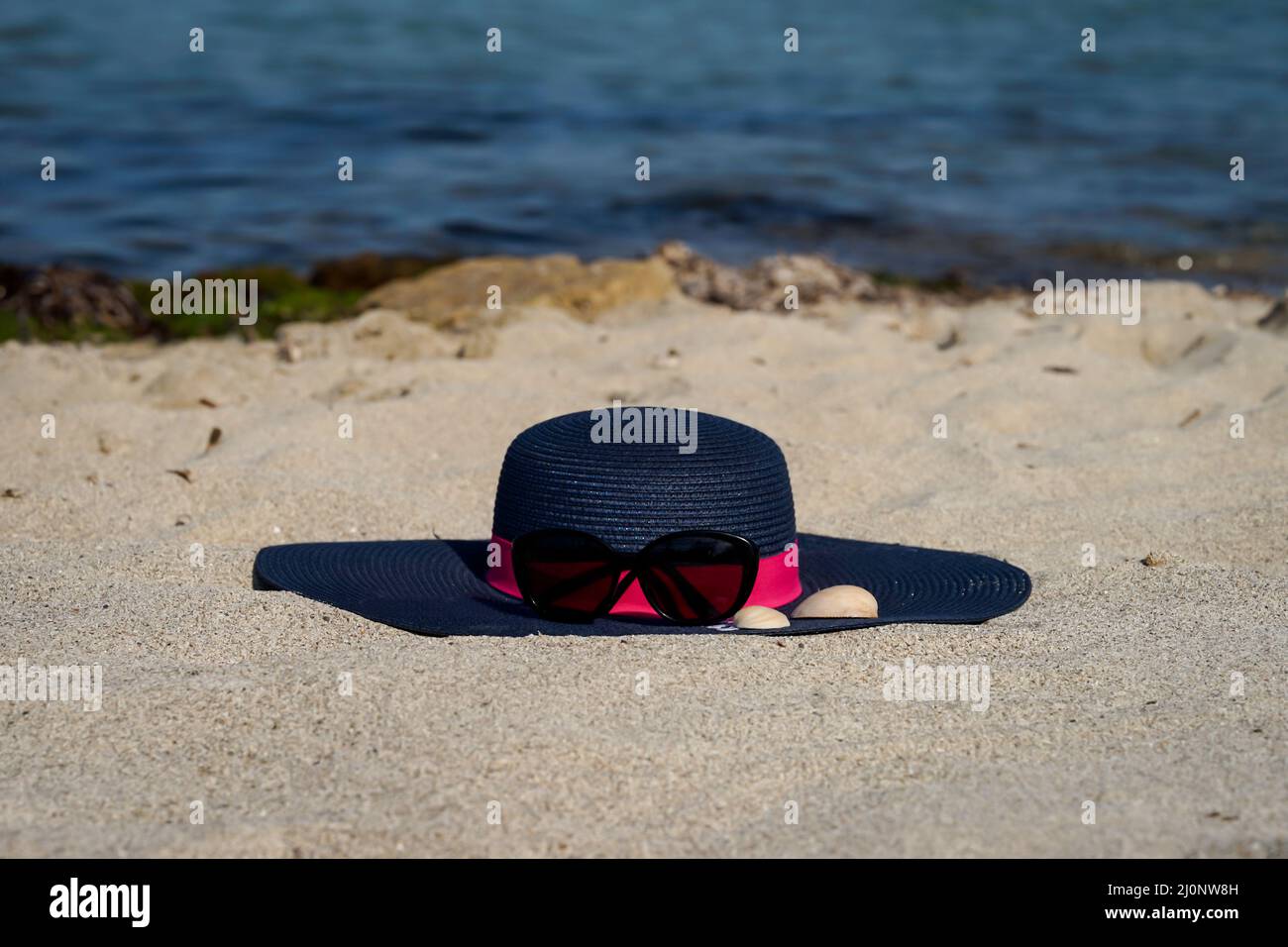 Ein Sonnenhut mit Sonnenbrille am Strand des Mittelmeers. Stockfoto