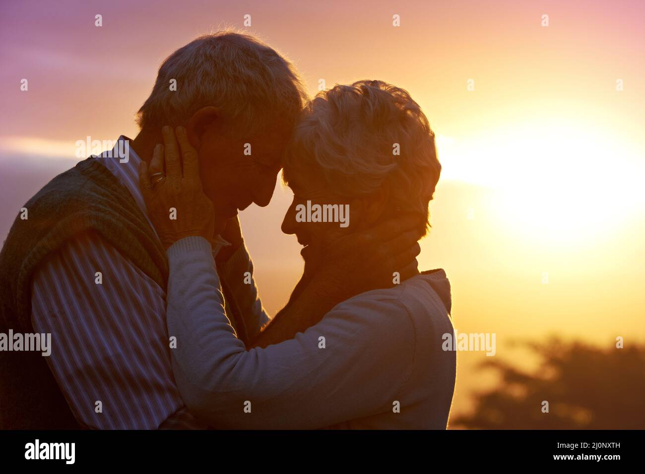 Liebe mich zart, liebe mich wahr Eine Aufnahme eines älteren Paares, das einen romantischen Moment bei Sonnenuntergang teilt. Stockfoto