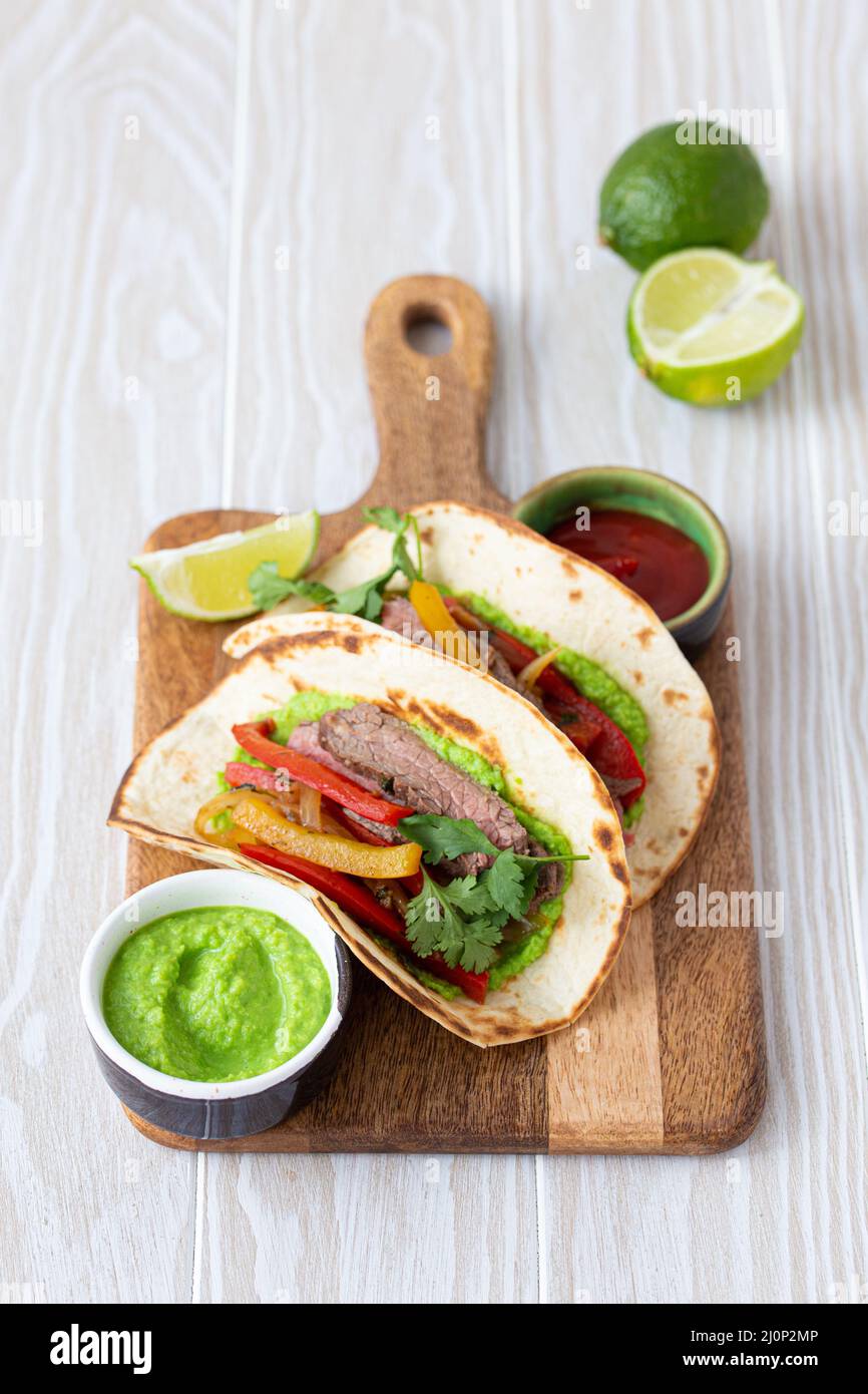 Mexikanisches Gericht Fajita Tacos auf Holz Schneidebrett auf weißem Tisch Stockfoto