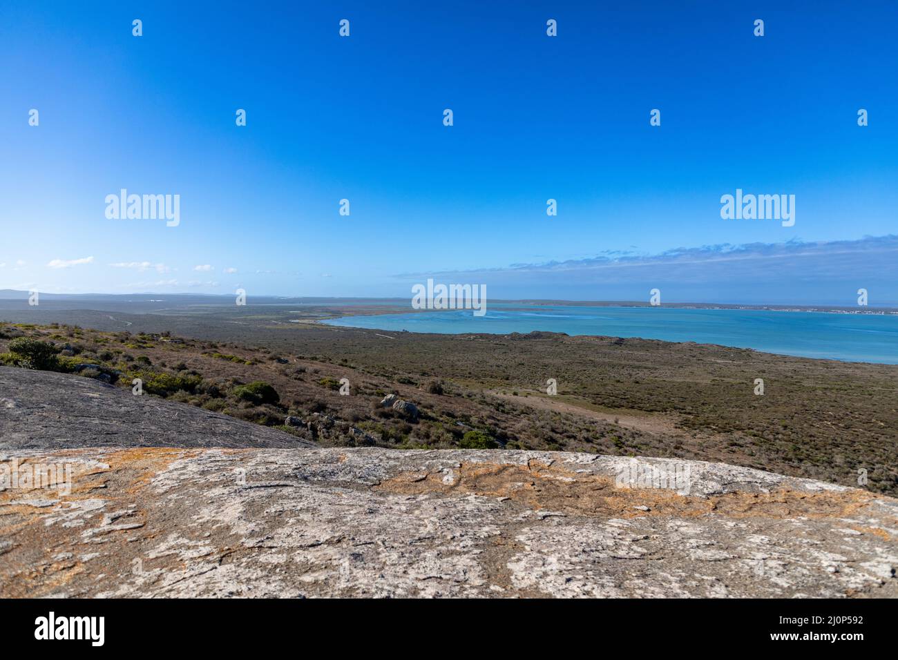 Selektiver Fokus türkisblaues Wasser der Langebaan Lagoon im West Coast Nationalpark in Südafrika. Großer Granitfelsen im Vordergrund Stockfoto