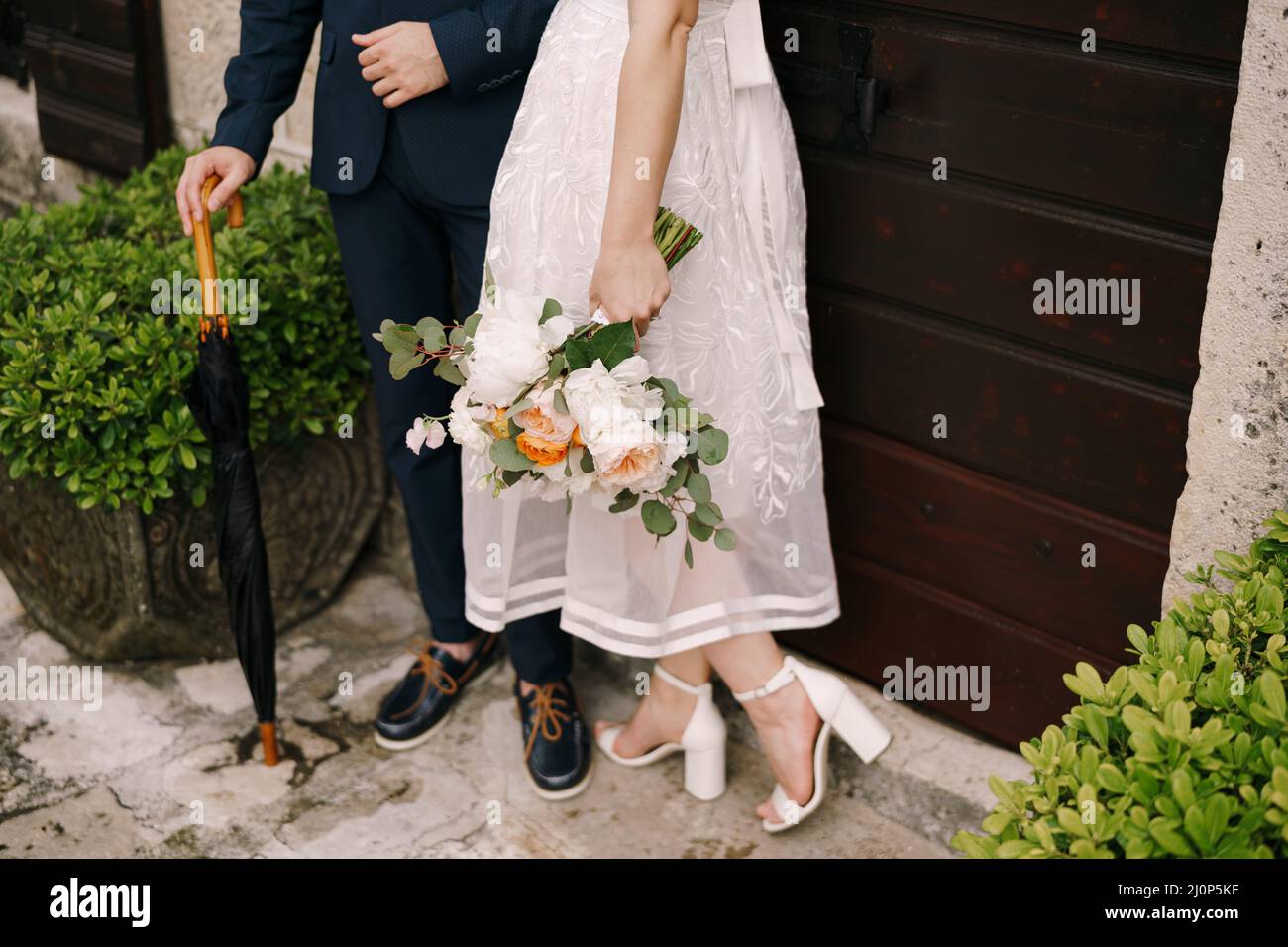 Braut und Bräutigam stehen an der Tür eines alten Steinhauses. Nahaufnahme Stockfoto