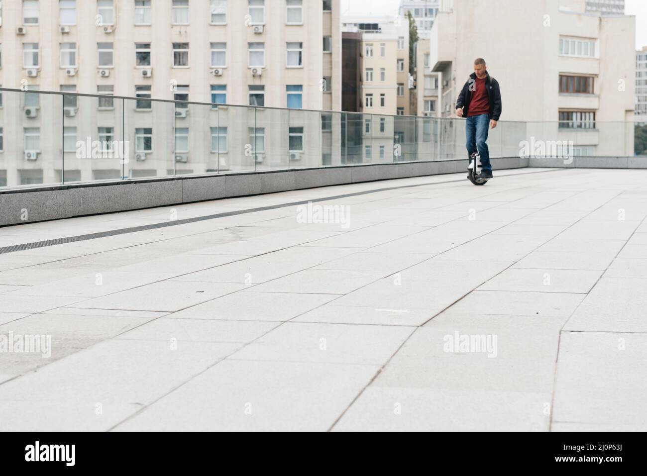 Mann, der schnell auf einem Elektro-Einrad auf der Stadtstraße fährt. Mobile tragbare individuelle Transport-Fahrzeug. Mann auf Elektro-Mono-Rad fahren schnell (EUC Stockfoto