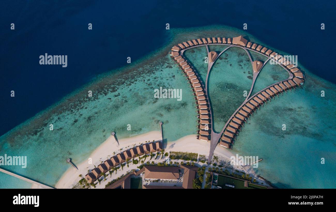 Luftaufnahme zu den Luxusvillen im Wasser unter klarem blauem Wasser im Herzen des Indischen Ozeans, Malediven Stockfoto