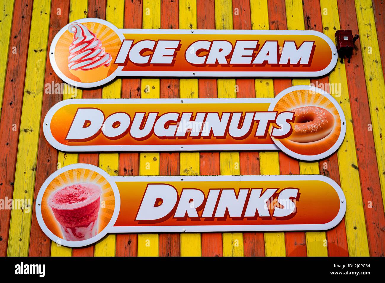 Gelbes und orangefarbenes Schild mit Werbung für Eis, Donuts und Getränke. Stockfoto