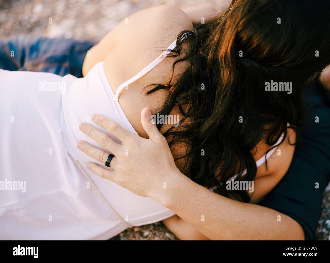 Mann und Frau umarmen sich, während sie auf dem Schotterweg im Park liegen Stockfoto