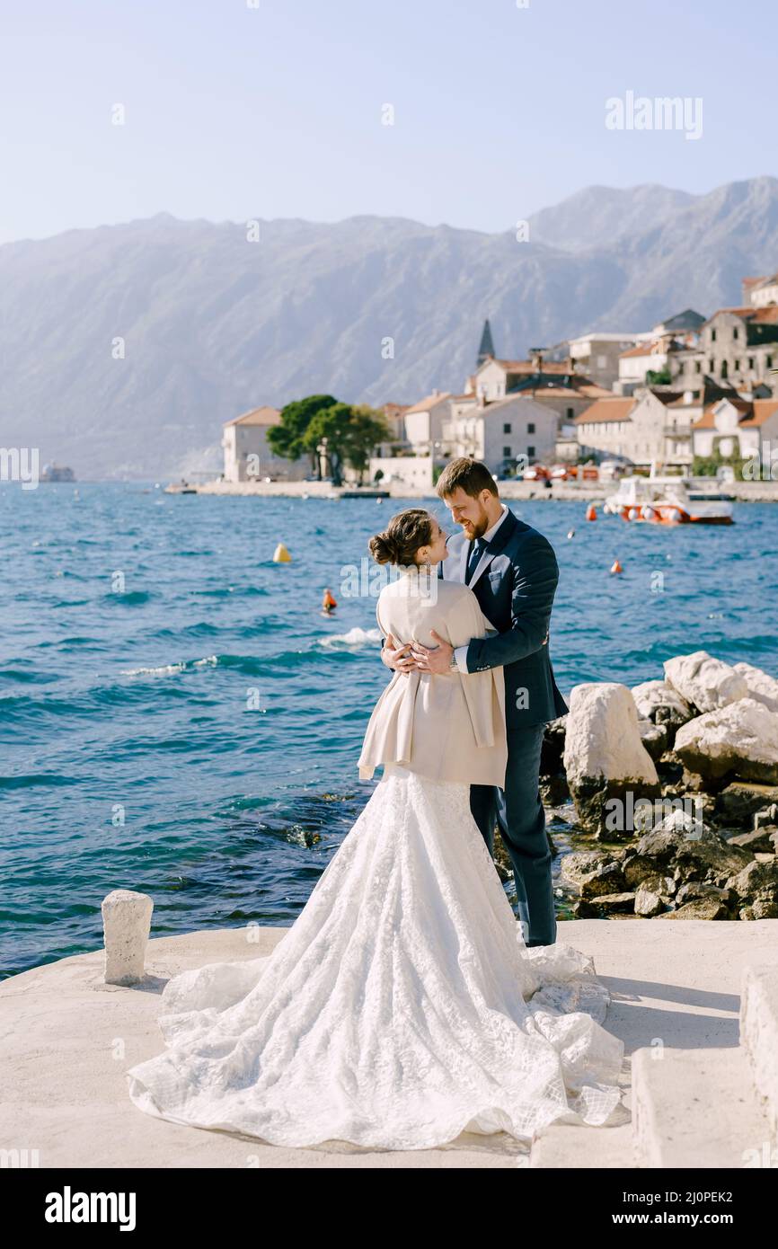 Braut und Bräutigam umarmen sich auf dem Hintergrund der Küste von Perast. Montenegro Stockfoto