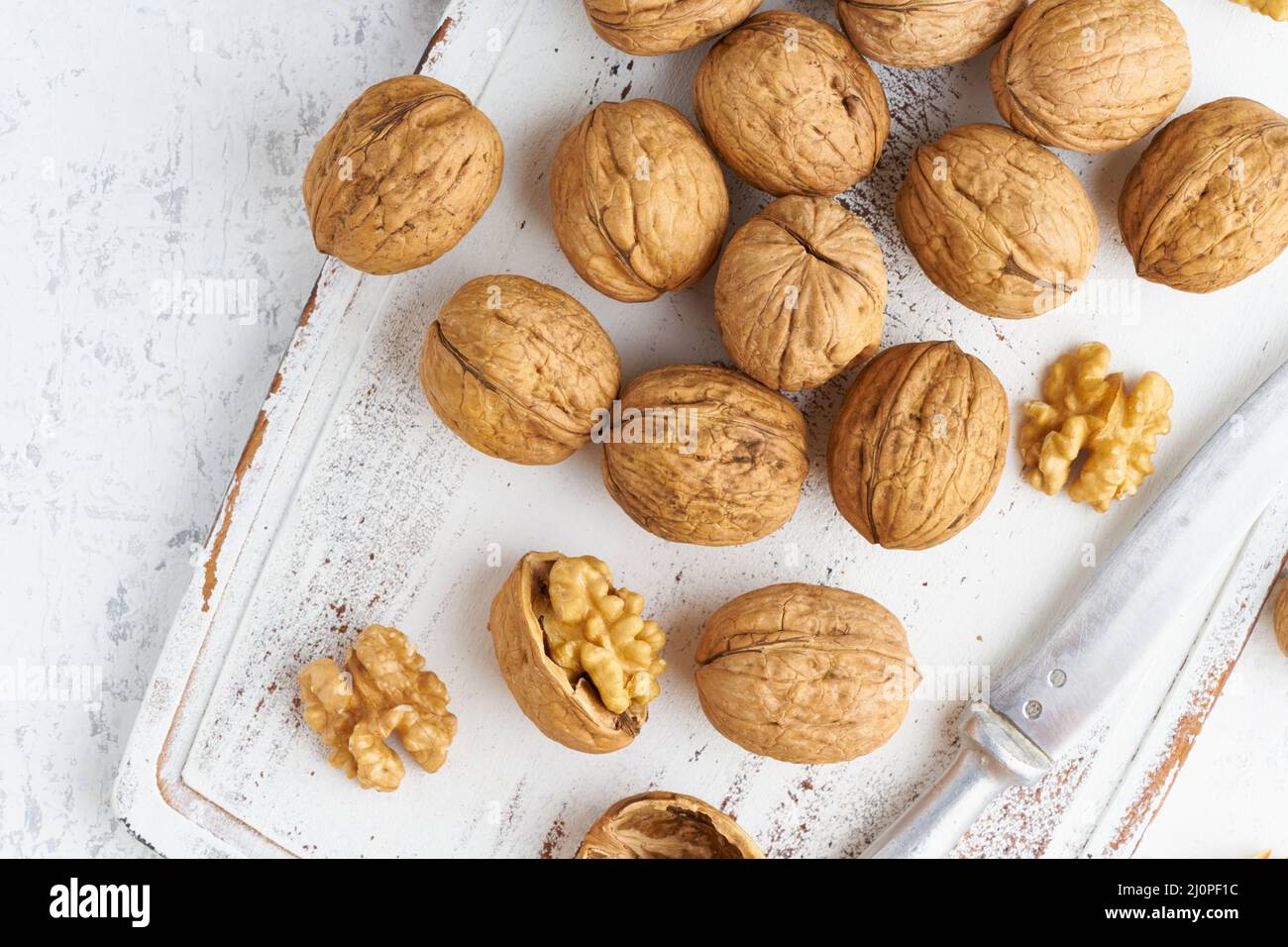 Nussbaum von oben im Endokarp, Schüssel mit Drupe in der Schale auf weißem Holzschneidebrett. Stockfoto