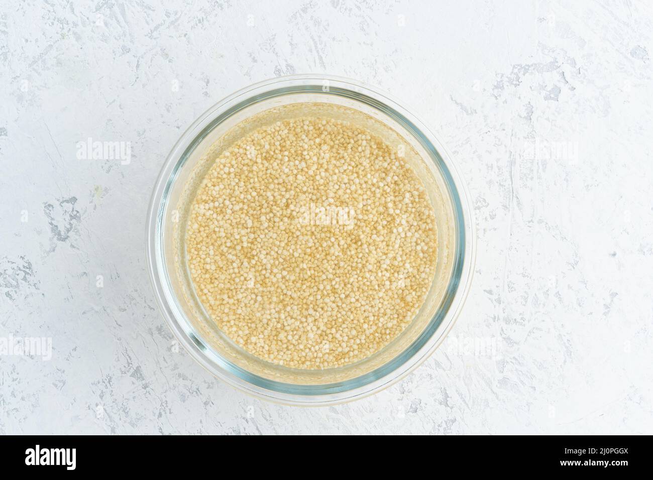 Einweichen von Quinoa-Müsli in Wasser, um Getreide zu gären und die Phytsäure zu neutralisieren Stockfoto
