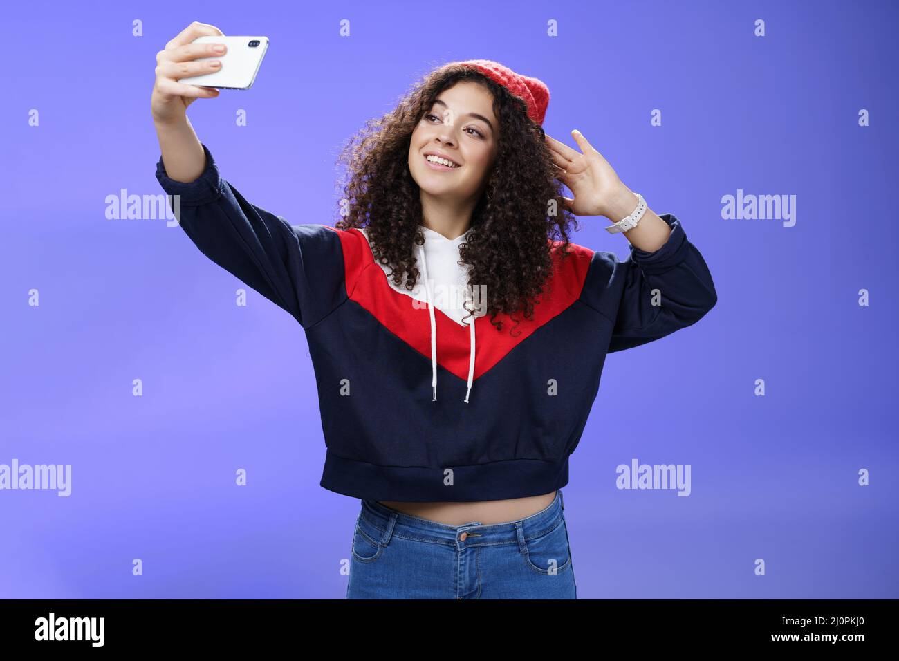 Nettes Mädchen macht Selfie Reise merken stehen in warmen Winter Beanie und Sweatshirt posiert als Ziehhand mit Smartphone und Stockfoto