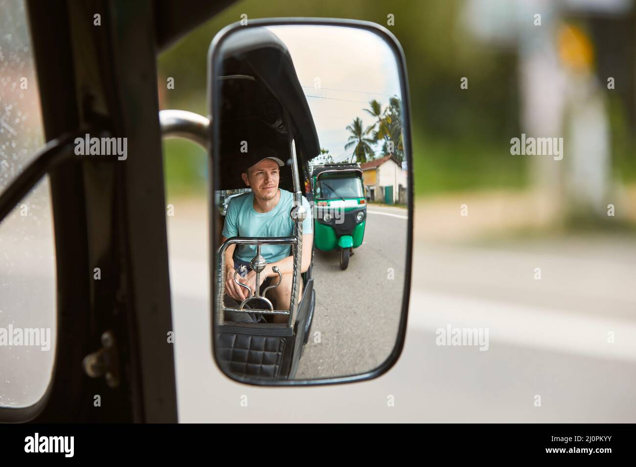 Mann, der mit dem Tuk Tuk reist. Spiegelung des Touristen im Spiegel des populären dreirädrigen Motorrades in Sri Lanka. Stockfoto