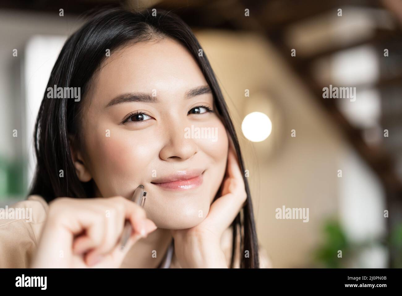 Porträt einer lächelnden asiatischen Frau Gesicht glücklich, halten Stift und grinsend, arbeiten oder Hausaufgaben Stockfoto