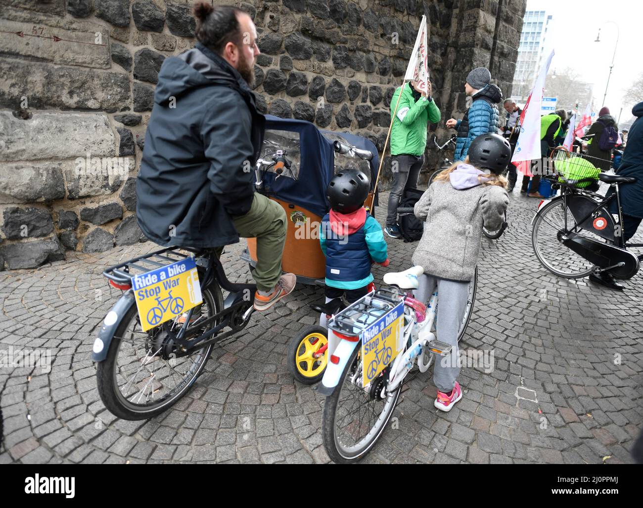 Köln, Deutschland. 20. März 2022. Unter dem Motto "Kidical Mass - Sichere Fahrradinfrastruktur und Freiräume für Kinder und Jugendliche" nehmen junge Radfahrer an einer Demonstration für bessere Radwege vor allem für Kinder in der Stadt Teil. Dabei haben viele Teilnehmer Banner in den ukrainischen Nationalfarben mit der Aufschrift "Ride a bike - Stop war" an ihren Rädern zur Unterstützung der Ukraine, die von Russland angegriffen wird. Quelle: Roberto Pfeil/dpa/Alamy Live News Stockfoto