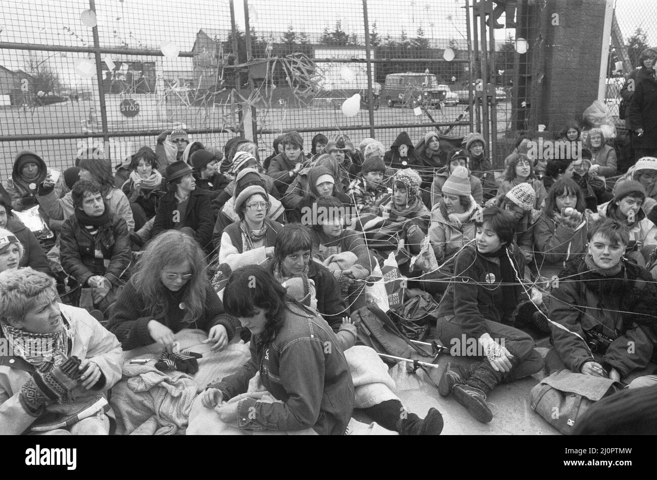 70.000 Demonstranten treffen sich zum "Women's Peace Camp" in Greenham Common und dem Atomwaffenstützpunkt in Aldermarston, um eine 14 Meilen lange Menschenkette zwischen den beiden Stützpunkten zu schaffen, um gegen die Entscheidung, amerikanische Marschflugkörper bei Greenham Common zu stationieren und die Verbreitung von Atomwaffen zu protestieren. Unser Bild zeigt: Frauen aus dem Friedenslager blockieren das Gelbe Tor in den RAF Greenham Common 1.. April 1983 Stockfoto