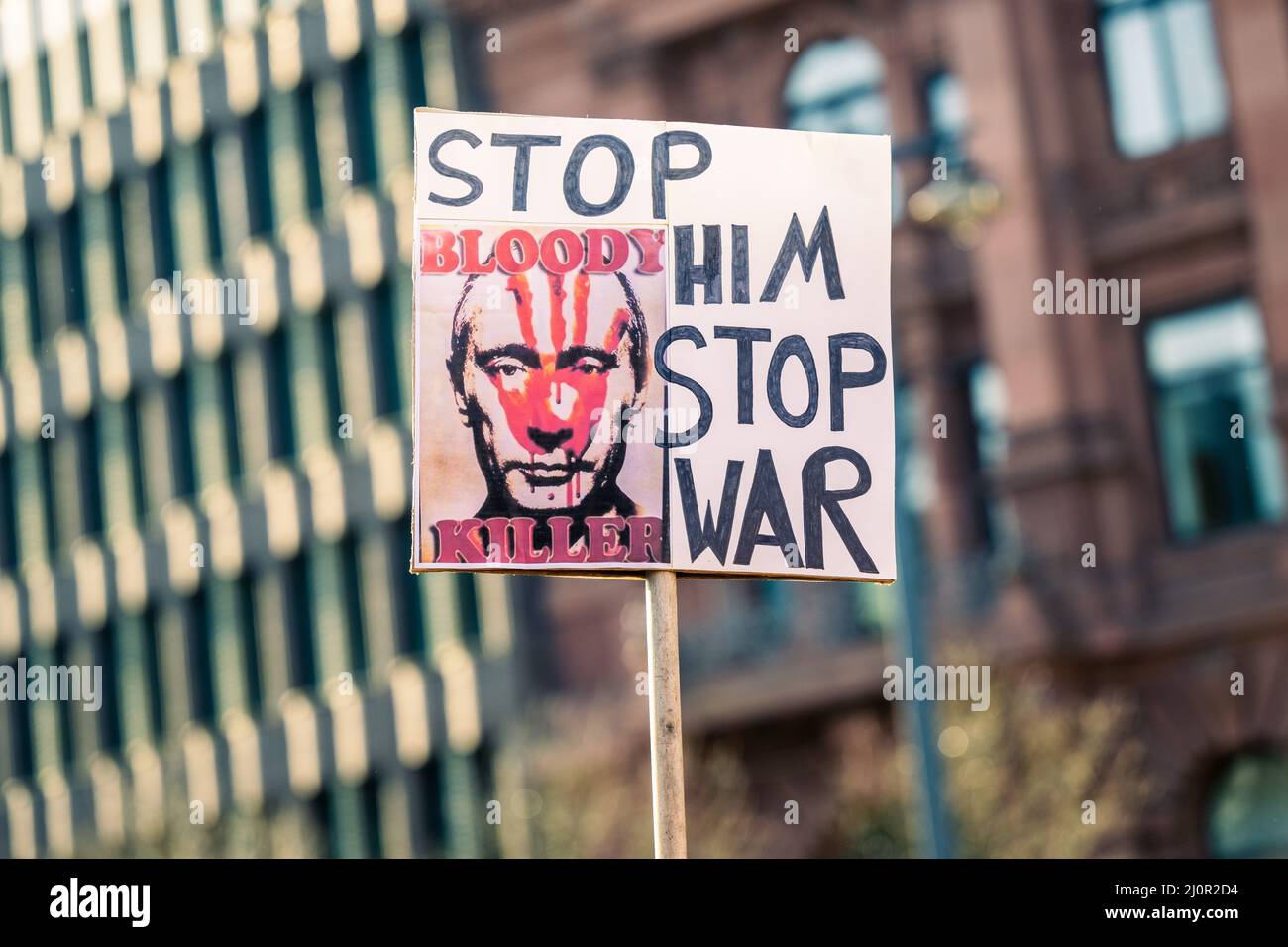 20. März 2022, Bremen: Einer der Demonstranten hält ein Schild mit einem Bild von Wladimir Putin mit der Aufschrift "Stoppt ihn - Stoppt den Krieg - Blutiger Mörder" hoch. Auf dem Domshof fand eine Kundgebung gegen den Krieg in der Ukraine statt. Foto: Mohssen Assanimoghaddam/dpa Stockfoto