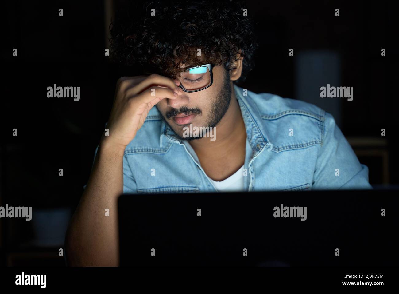 Müde, müde, müde, junger indischer Mann, der eine Brille trägt und spät am Computer arbeitet. Stockfoto