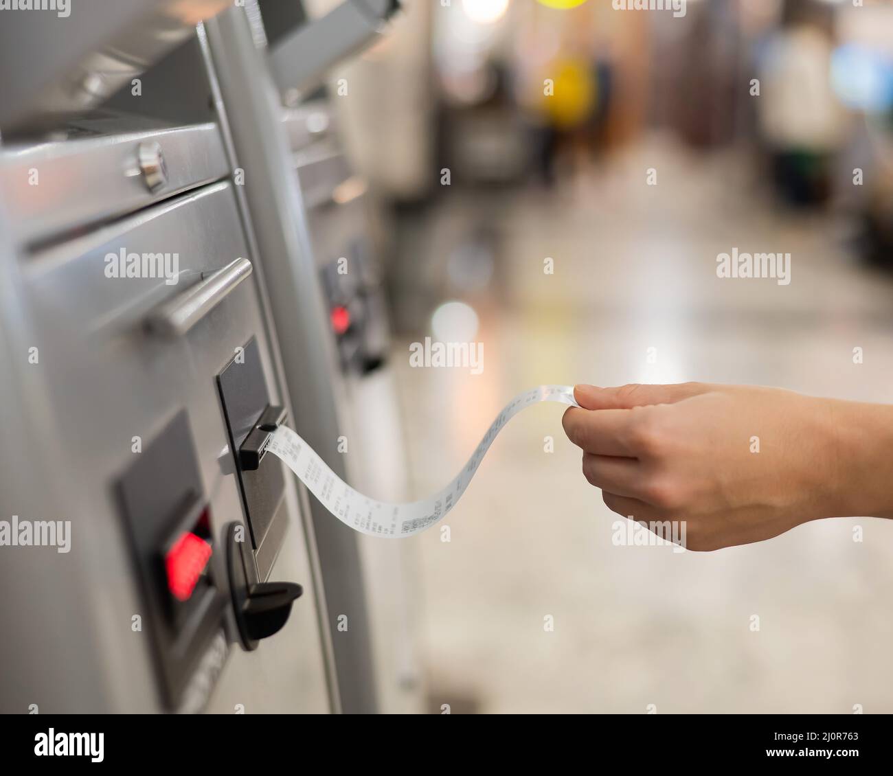 Eine Frau nimmt ein Zugticket von einem Selbstbedienungskartenschalter. Stockfoto