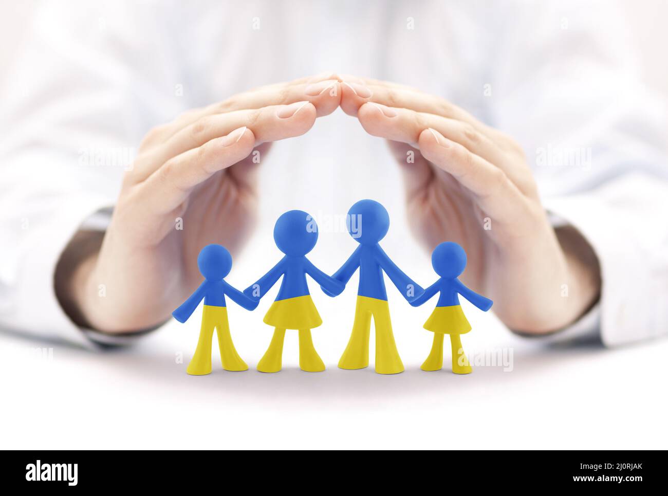 Familienfiguren mit den Farben der ukrainischen Flagge, die von Händen bedeckt sind Stockfoto