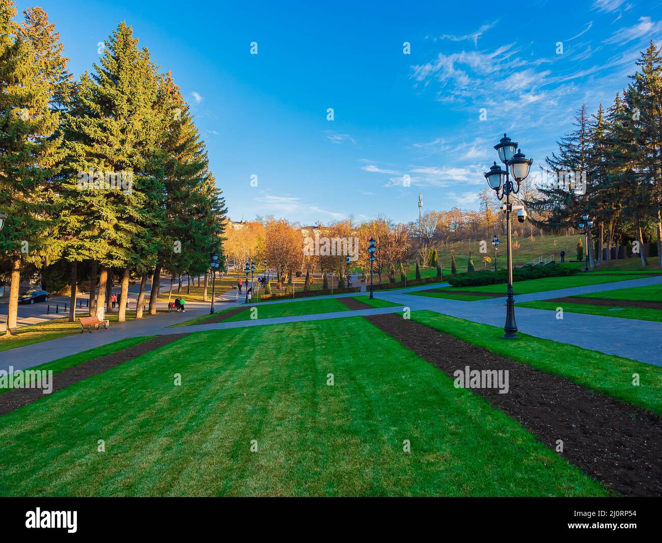 Wandergebiet mit grünen gepflegten Rasenflächen Laternen und Nadelbäumen Stockfoto