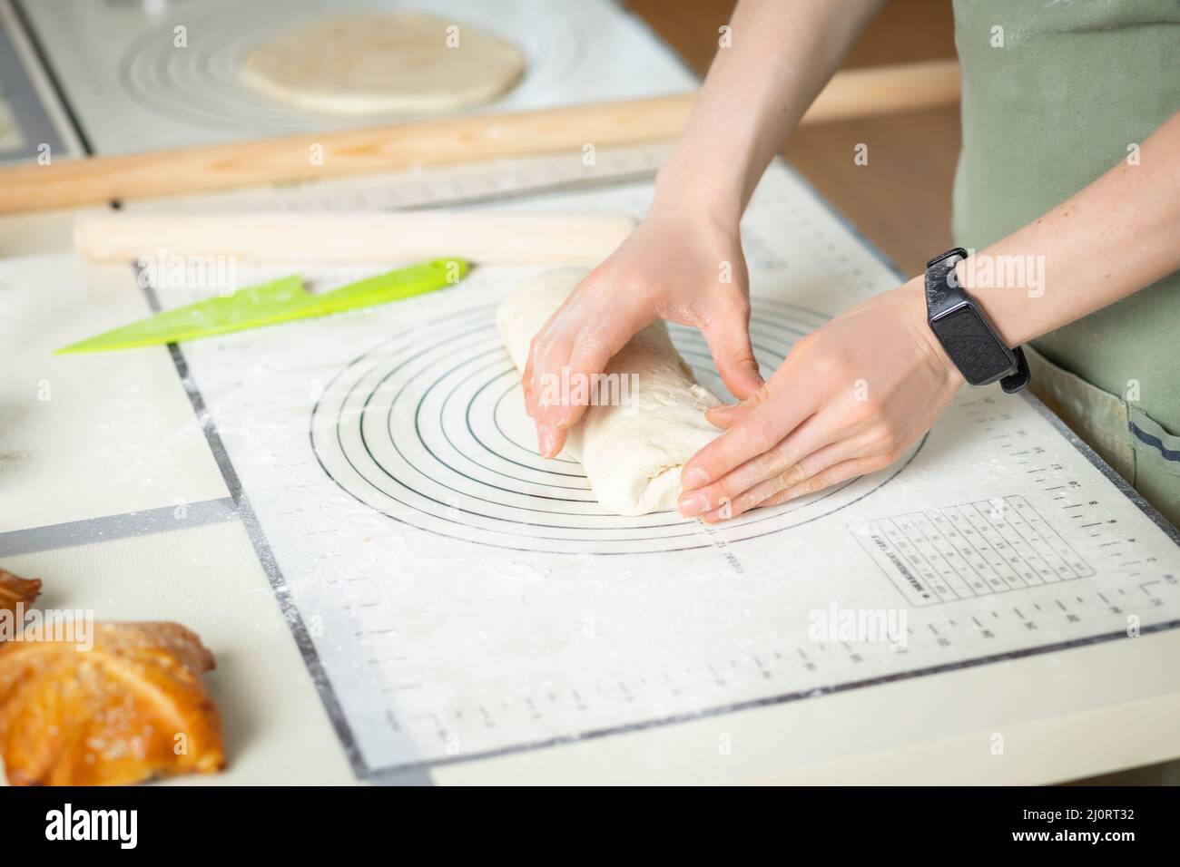 Blick auf Frauenhänden mit elektronischem Fitnessarmband, das hausgemachte Kuchen kocht. Stockfoto