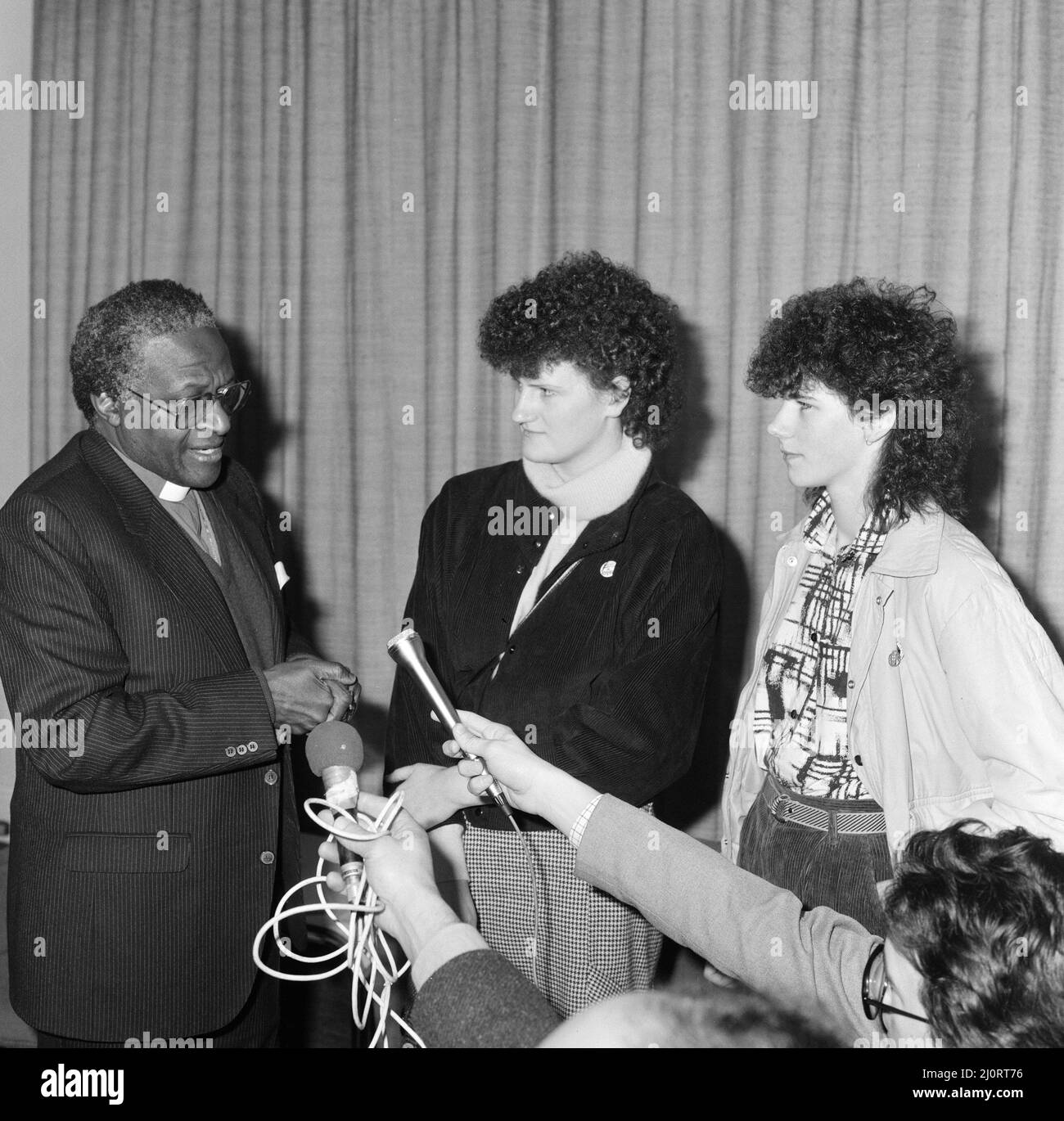 Bischof Desmond Tutu am Flughafen London, auf dem Weg nach Oslo, um seinen Nobelpreis zu erhalten, flankiert von irischen Frauen, Mary Manning (links) und Karen Gearon. 8.. Dezember 1984. Stockfoto