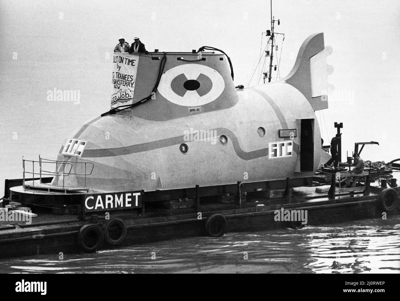 The Yellow Submarine in Liverpool, eine große Modelldarstellung des U-Bootes aus dem Animationsfilm Yellow Submarine, inspiriert vom gleichnamigen Lied auf dem Beatles-Album Revolver. Es wurde von einer Gruppe von etwa 80 Auszubildenden von Cammell Laird's Werft für die Ausstellung auf dem International Garden Festival in Liverpool im Jahr 1984 gebaut. Bild zeigt: Das U-Boot auf dem Fluss Mersey kurz vor dem Transport zum Messegelände nach dem Bau der Cammell Laird Werft in Birkenhead. 29.. Februar 1984. Stockfoto