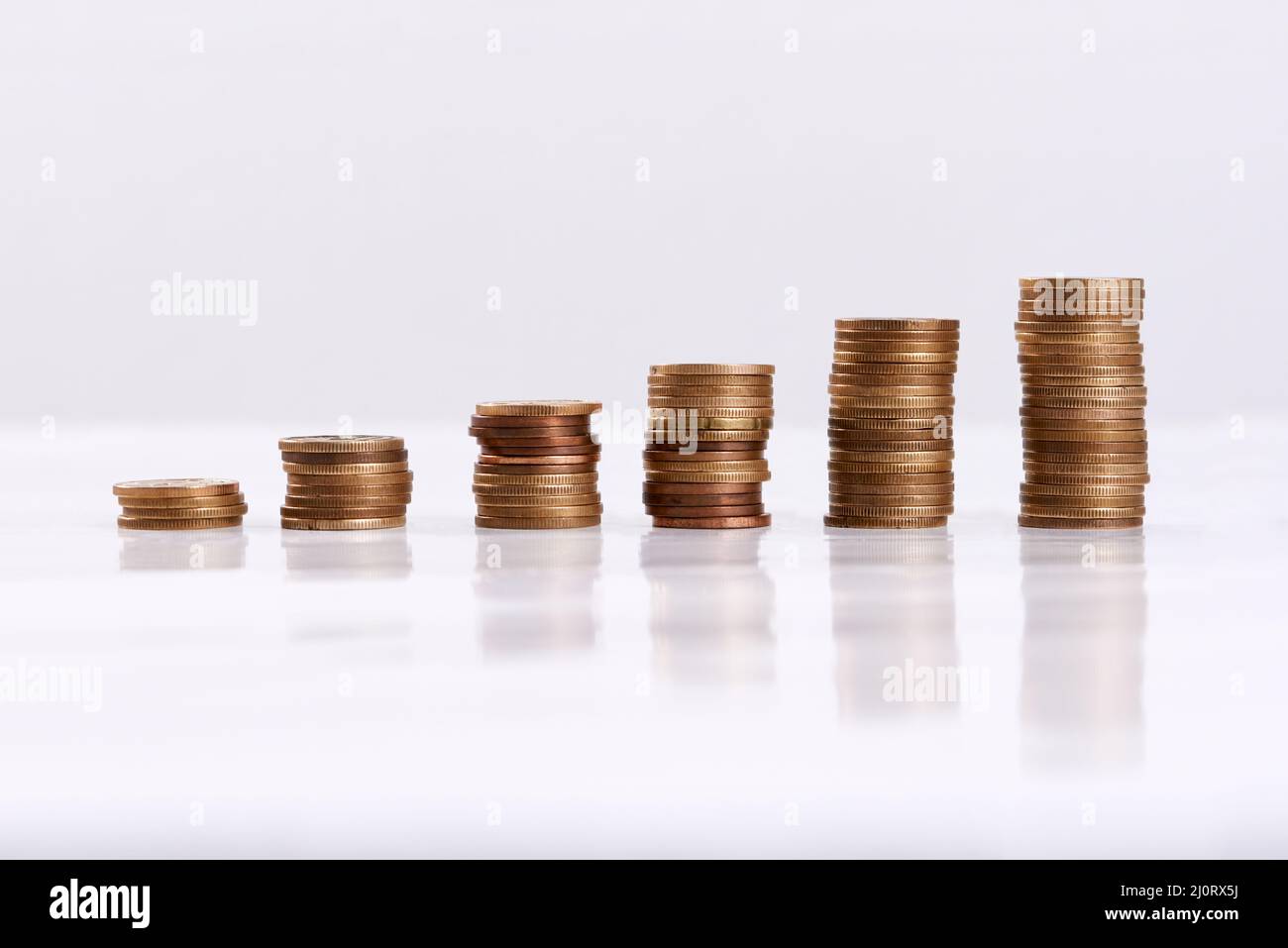 Jeder kleine Teil hilft. Studioaufnahme von Münzsäulen, isoliert auf weißem Hintergrund. Stockfoto