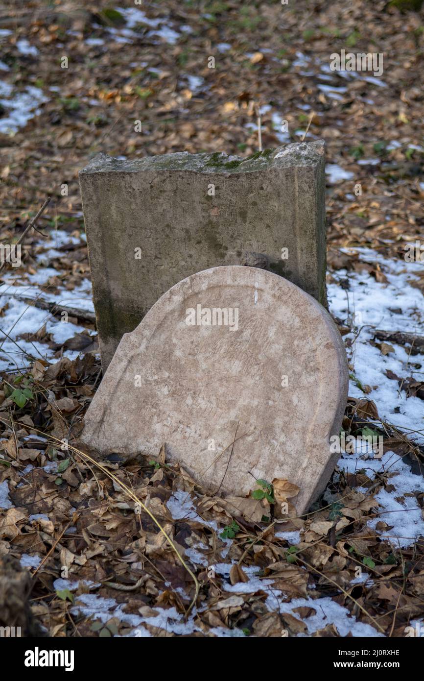 Alte alte alte verlassene jüdische Friedhof im Wald im Winter. Gealterte Grabsteine oder Grabsteine auf dem Friedhof. Stockfoto