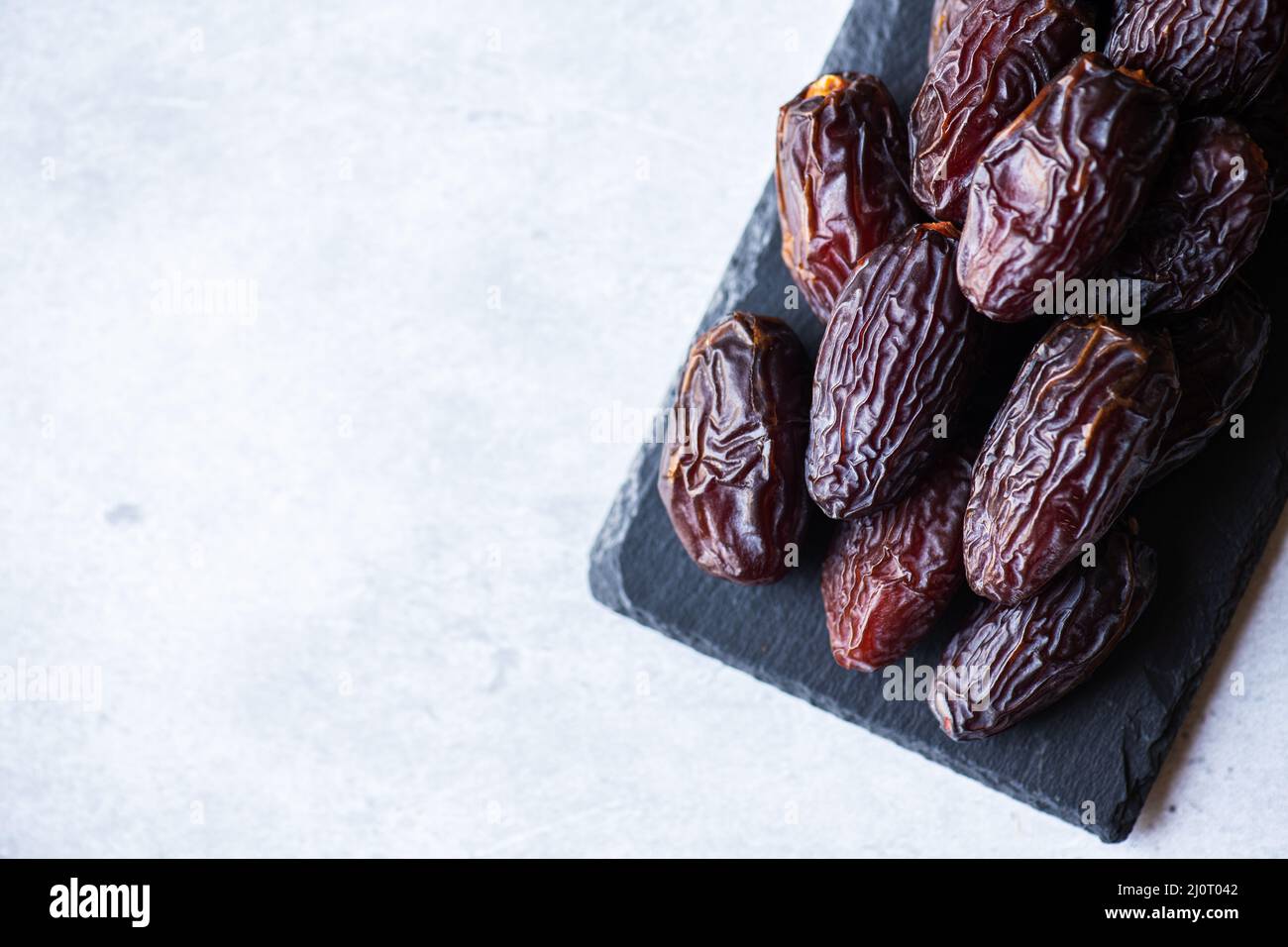 Medjoul datiert auf einem schwarzen Schiefertafel auf grauem Hintergrund. Draufsicht, Kopierbereich. Stockfoto