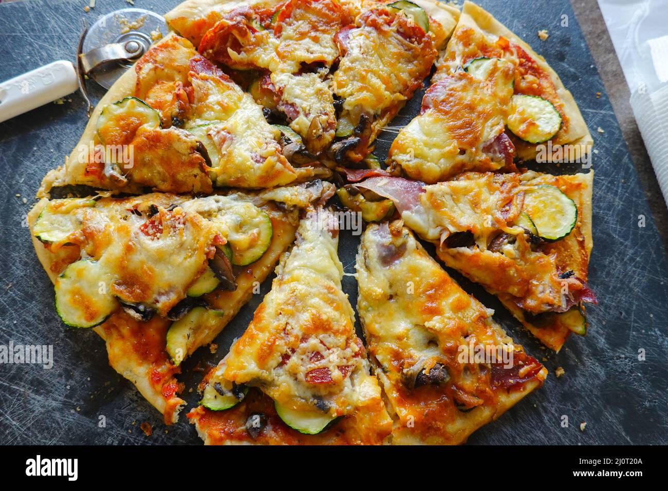 Hausgemachte Pizza in Scheiben mit einem Pizzarad. Stockfoto