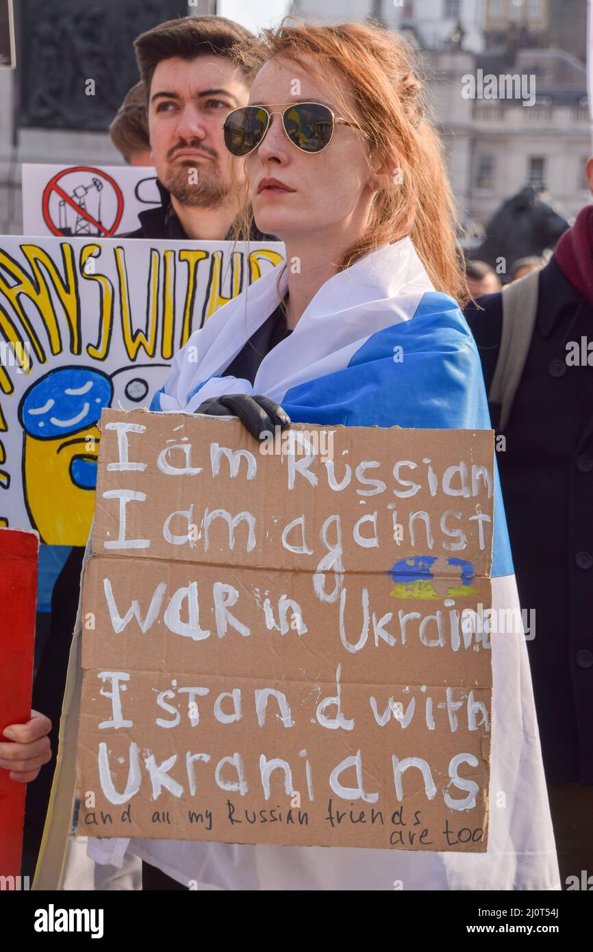 London, Großbritannien. 20.. März 2022. . Ein russischer Protestler, der in die symbolische blau-weiße russische Flagge gehüllt ist und die rote Farbe entfernt hat, hält ein Antikriegszeichen. Auf dem Trafalgar-Platz versammeln sich weiterhin große Menschenmengen zur Unterstützung der Ukraine, während Russland seinen Angriff verstärkt. Kredit: Vuk Valcic/Alamy Live Nachrichten Stockfoto