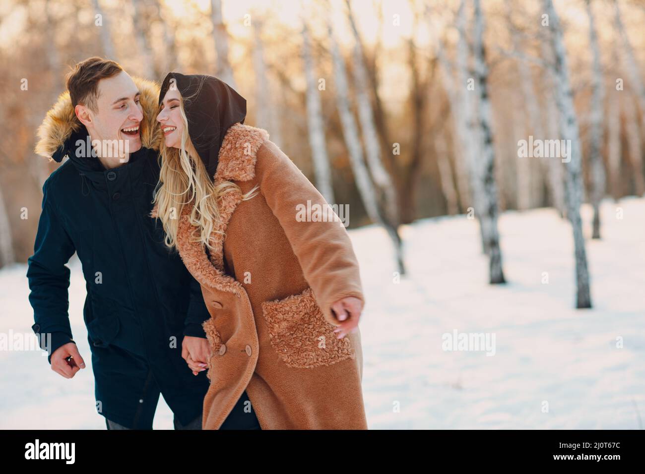 Liebevolles junges Paar, das im Winterwaldpark spielt und Spaß hat Stockfoto