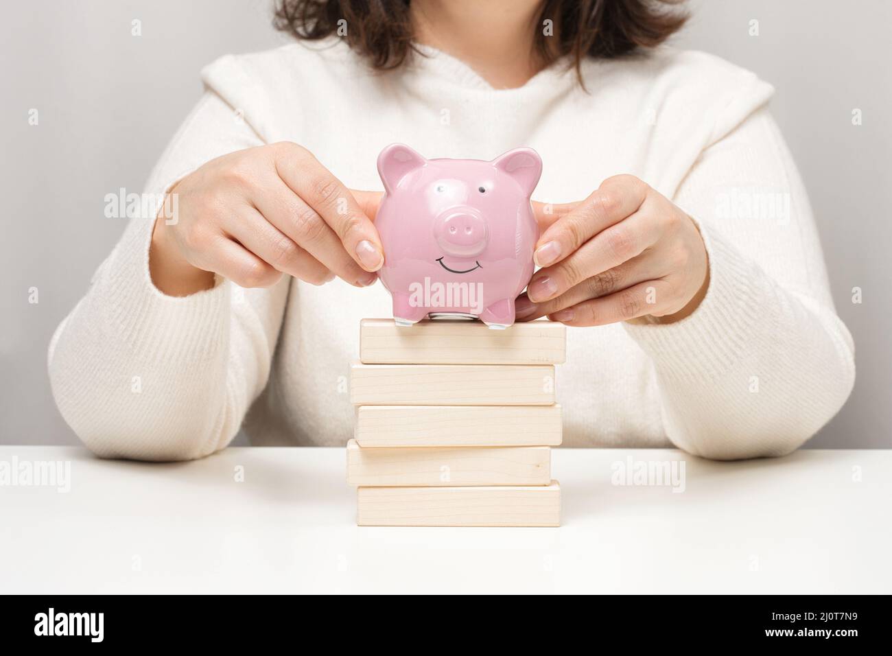 Pinkfarbenes Sparschwein aus Keramik und Holzklötze. Konzept der Erhöhung des Zinses auf eine Einzahlung in einer Bank, hohe Rendite auf Investitionen, lar Stockfoto