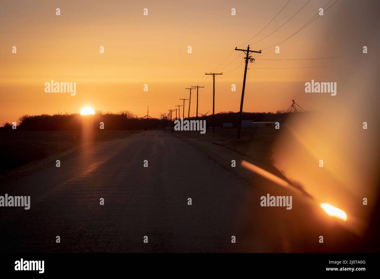 Telefonmasten entlang einer Landstraße im amerikanischen Mittleren Westen bei Sonnenuntergang Stockfoto