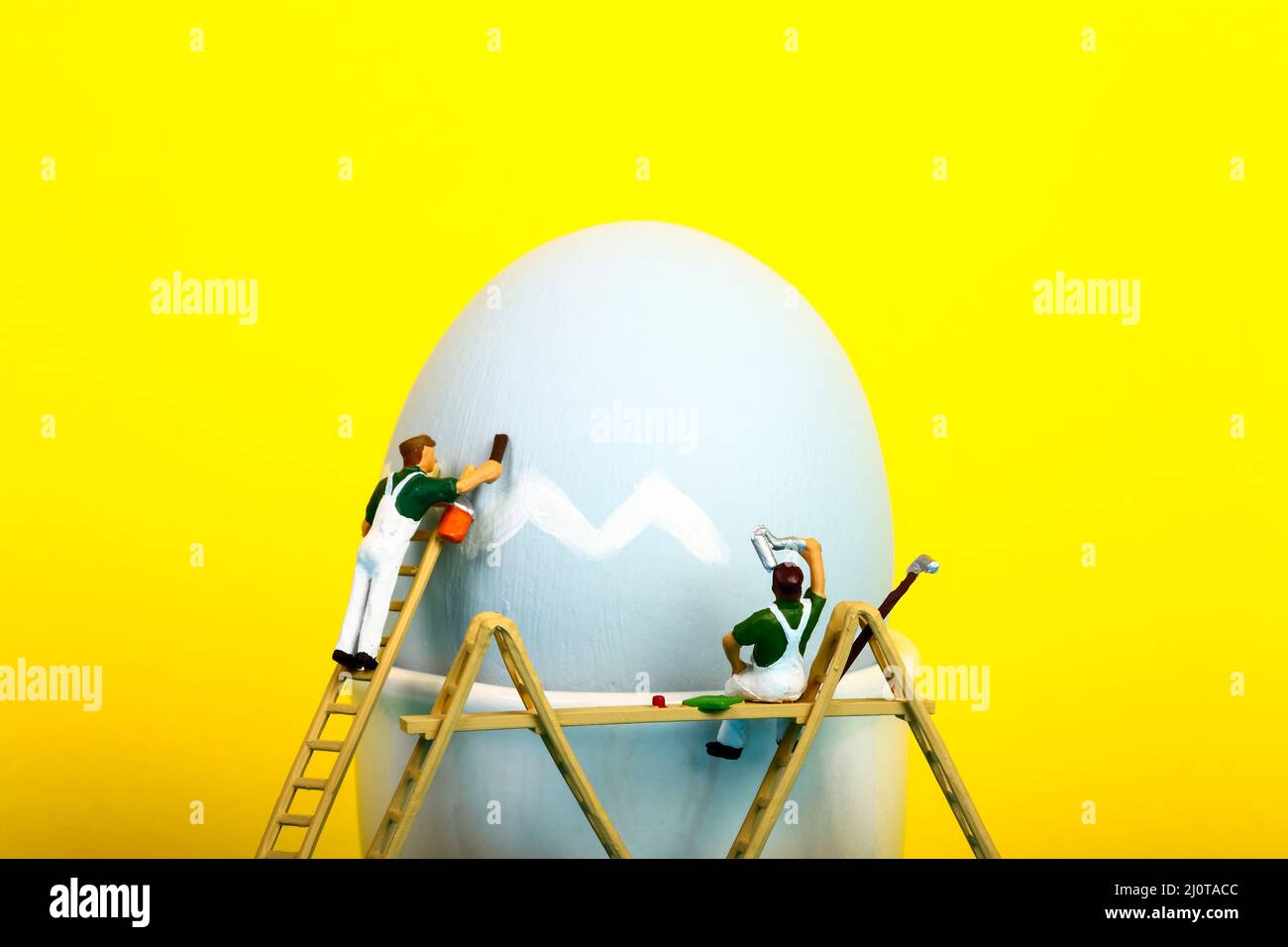 Konzeptuelles Bild von Miniaturfiguren Menschen malen ein Hühnereier für Ostern Stockfoto