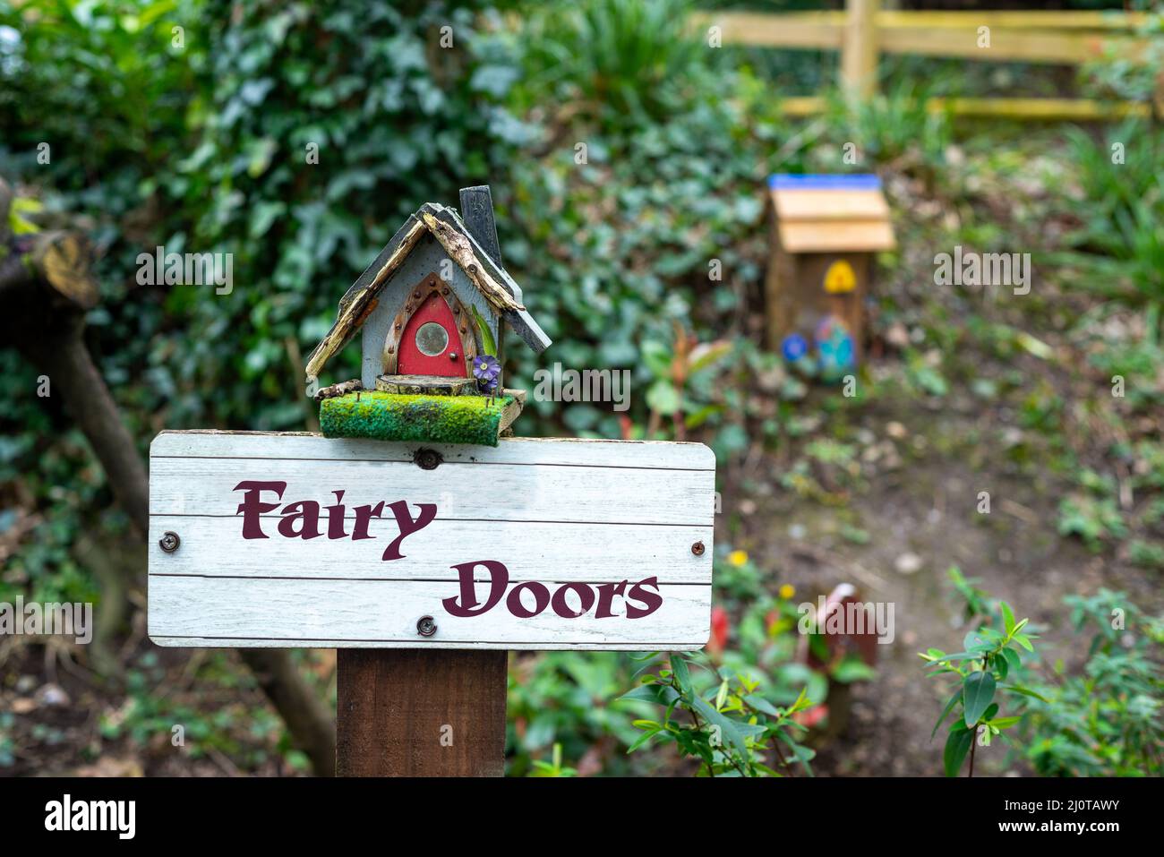 Feentüren Holzpfosten mit Feenhäusern in charmanten Outdoor-Feengarten in Irland. Stockfoto