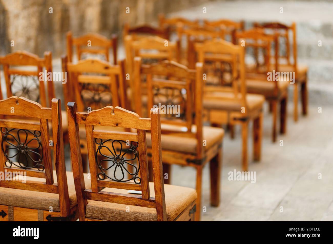 Holzstühle mit Mustern auf der Rückseite stehen in Reihen Stockfoto