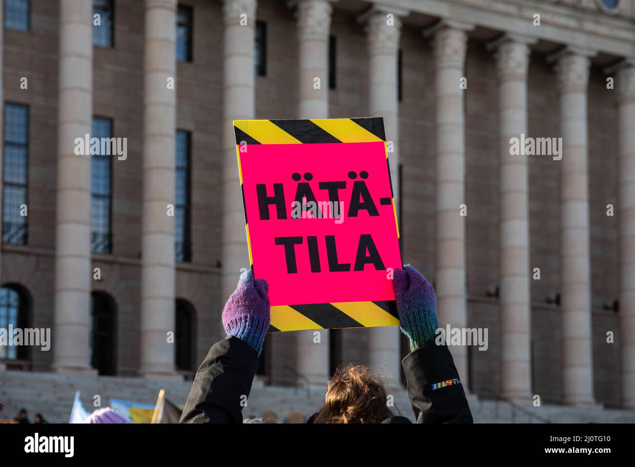 Hätätila. Demonstrator mit einem Schild vor dem Eduskuntatalo oder dem Parlamentsgebäude am Lunastakaa lupaukset-Protest gegen den Klimawandel. Helsinki, Finnland. Stockfoto