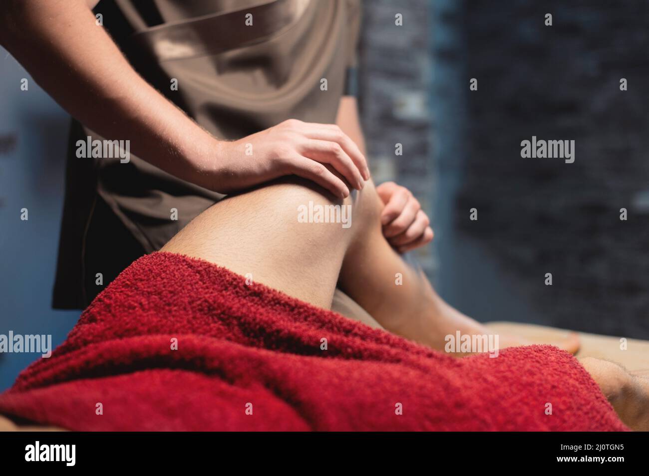 Professionelle männliche Sportmassage der Hüfte und des Knies in einem dunklen Massageraum. Premium-Massagen. Speicherplatz kopieren Stockfoto
