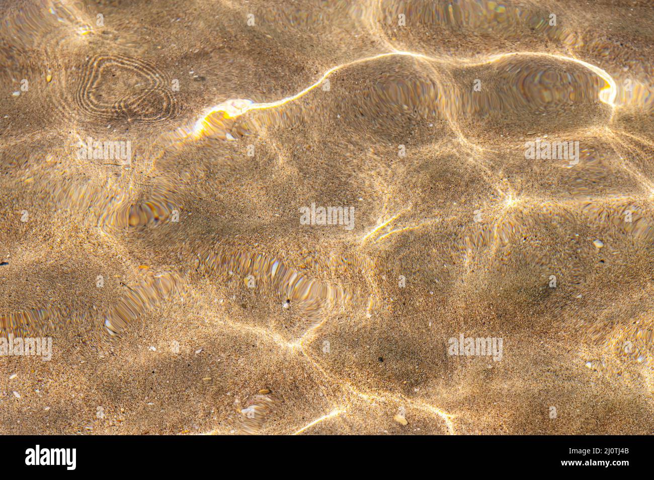Meereshintergrund Meeresboden mit Sonneneinstrahlung. Blick durch das sandige Grundwasser Stockfoto