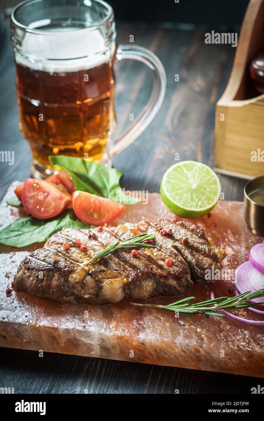 Gebratenes Schweinesteak auf himalaya-Salzblock mit Bier Stockfoto