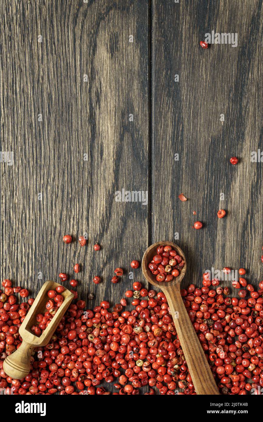 Rote Pfefferkörner mit Schaufel und Löffel auf Holzhintergrund mit Kopierraum. Hintergrund der Speisen Stockfoto