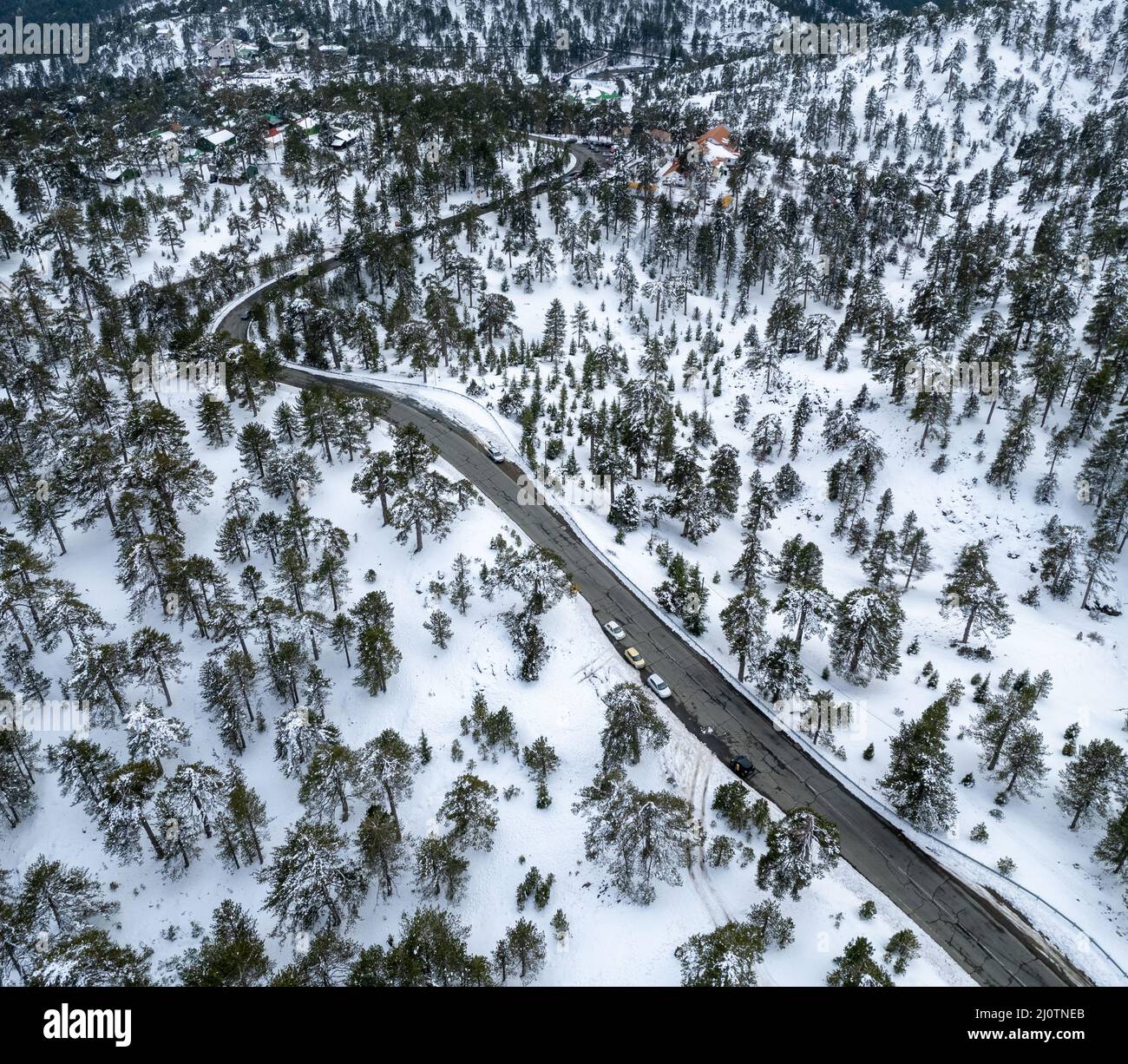 Drohnenaufnahme einer asphaltierten Autobahn, die im Winter den verschneiten Berg überquert. Stockfoto