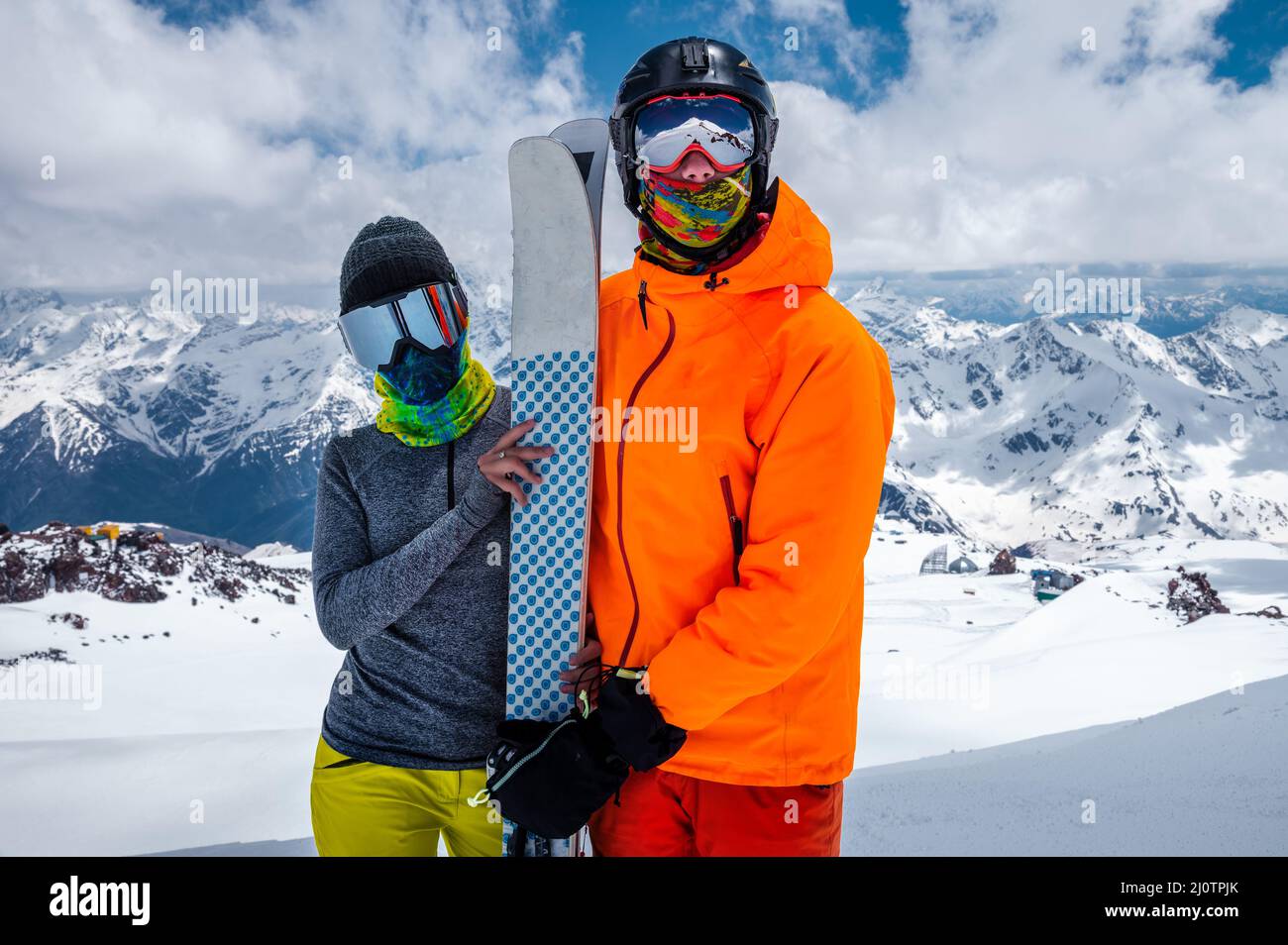 Junge Paar Skifahrer Mann und Frau unkenntlich in Snowboarding Ausrüstung Masken auf dem Hintergrund der schneebedeckten Berge h Stockfoto