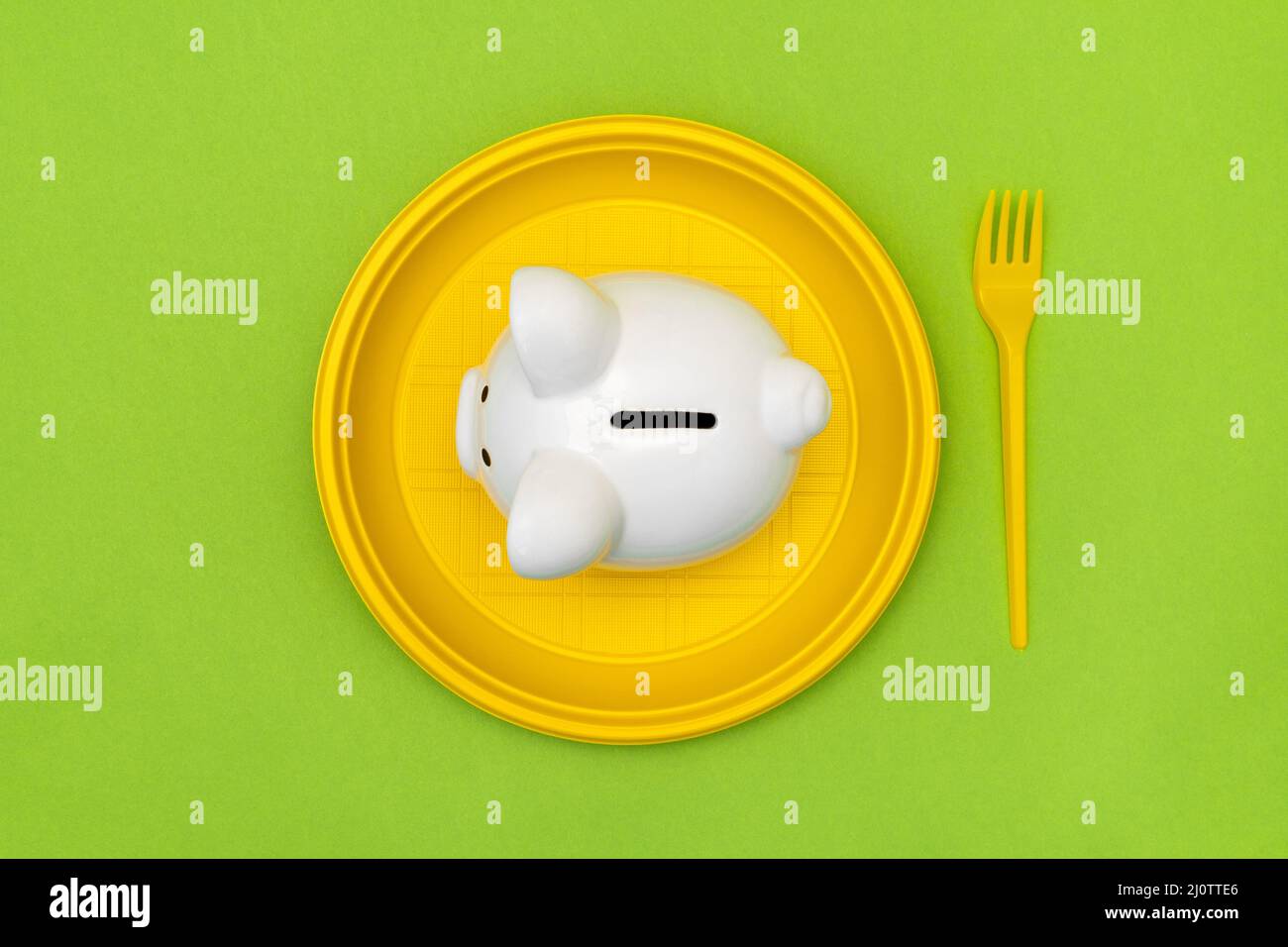 Sparschwein auf dem gelben Einwegteller mit einer Gabel Stockfoto