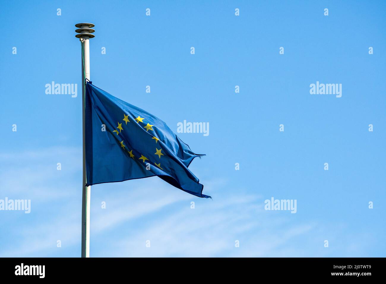 Verschlissene EU-Flagge vor blauem Himmel, keine Wolken Stockfoto