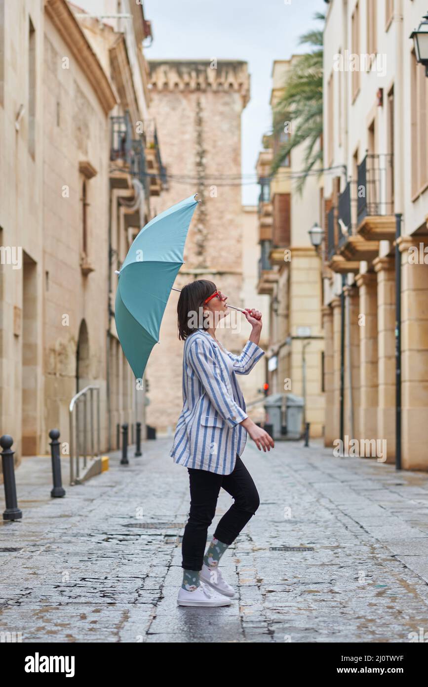 Frau, die an einem regnerischen Tag mit Regenschirm die Straße entlang läuft Stockfoto