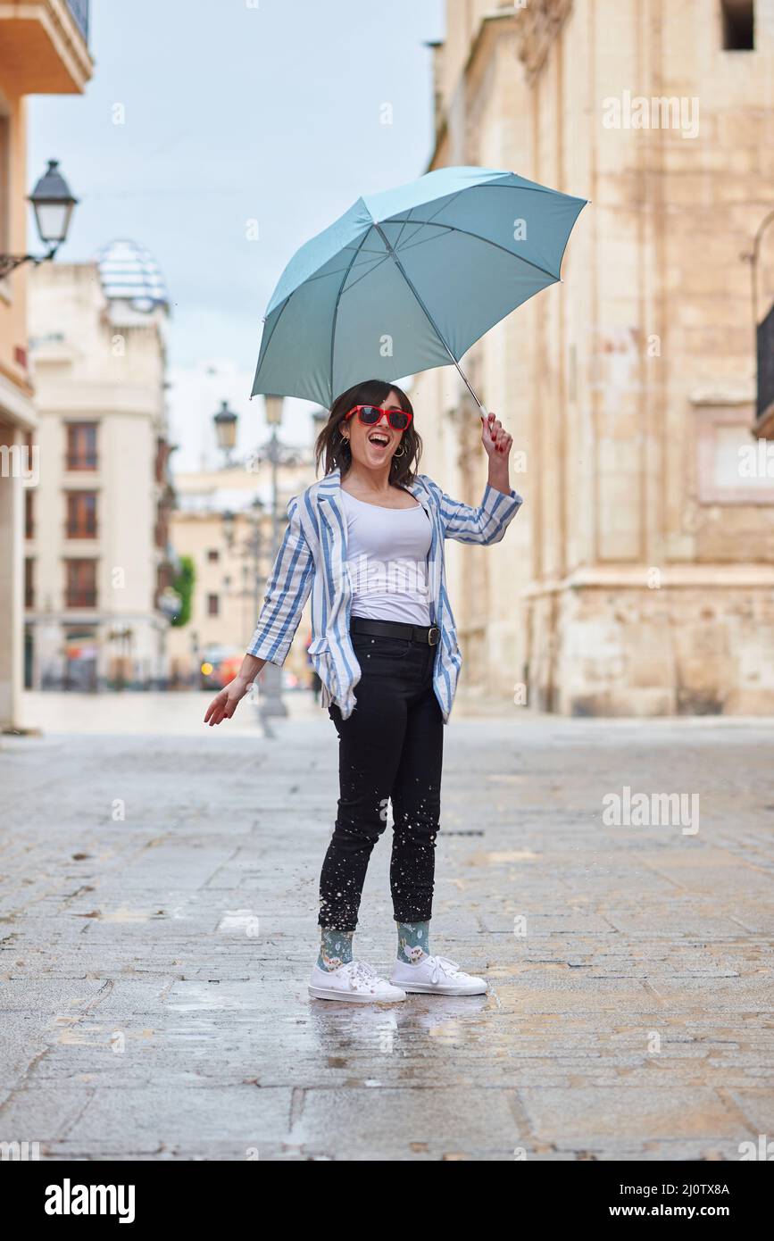 Frau, die an einem regnerischen Tag über eine Pfütze springt Stockfoto