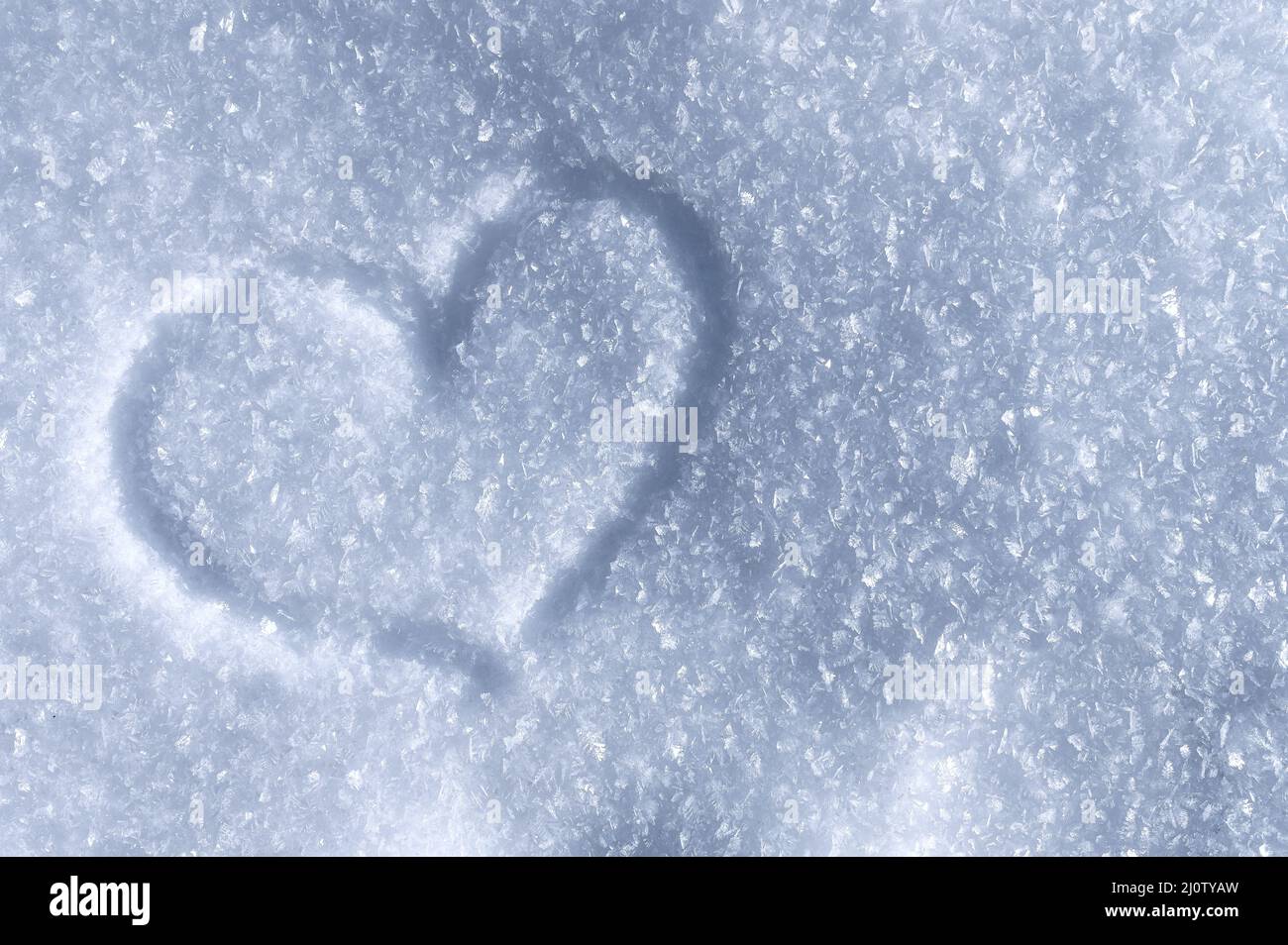 Winterhintergrund von glitzernden Schneekristallen in der Sonne. Symbol der Liebe Herz Stockfoto